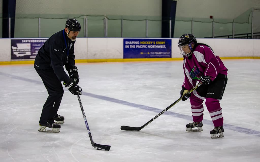 Coach teaching adult hockey player